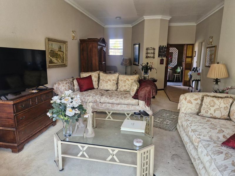 A spacious living room featuring crown molding and a glass block window, offering a traditional layout with potential for modern updates.