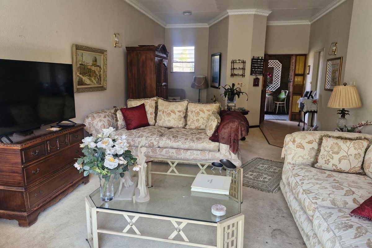 A spacious living room featuring crown molding and a glass block window, offering a traditional layout with potential for modern updates.