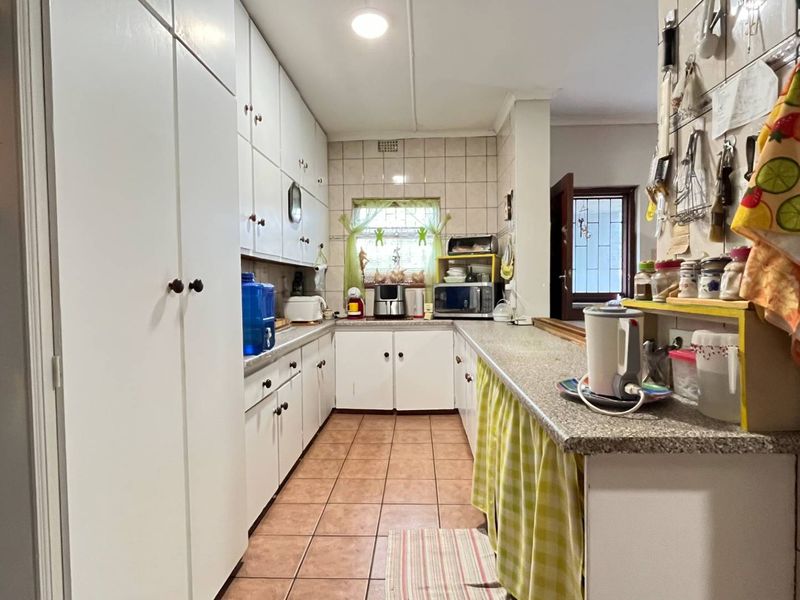A functional kitchen featuring extensive built-in cabinetry, tiled flooring, and a tiled backsplash, offering a practical layout with ample storage space.