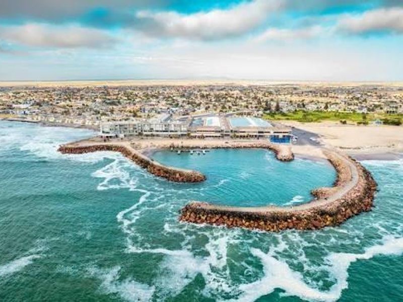 An aerial view of the coastal property, showcasing its proximity to the ocean, the breakwater, and the surrounding landscape.