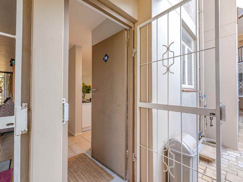 Apartment entrance featuring a security gate and a solid door leading into a tiled interior hallway.