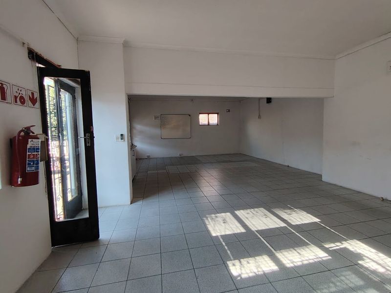 An open-plan office space featuring tiled flooring, neutral walls, and a security entrance, providing a versatile layout for various business configurations.