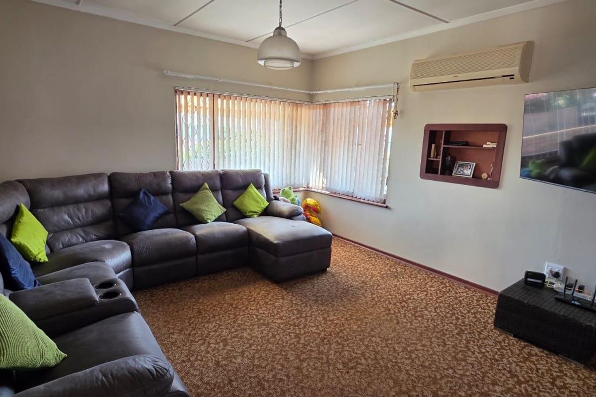 A comfortable living room featuring carpet flooring, a wall-mounted air conditioning unit, and a built-in wall niche for display.