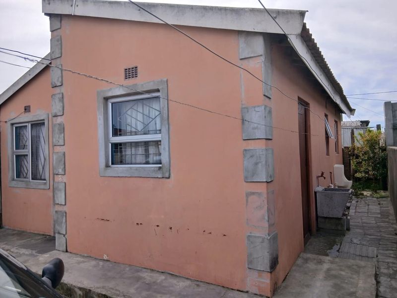 Rear exterior view of the house featuring concrete corner detailing, an external wash basin, and aluminium window frames with security bars.