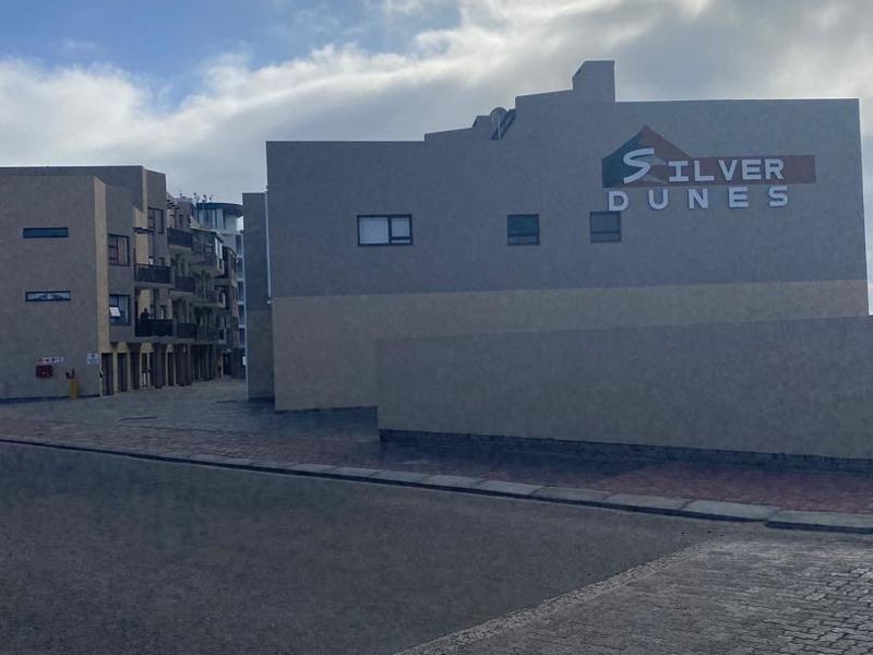 Exterior view of the Silver Dunes apartment complex, featuring paved access and multi-level residential units with balconies.