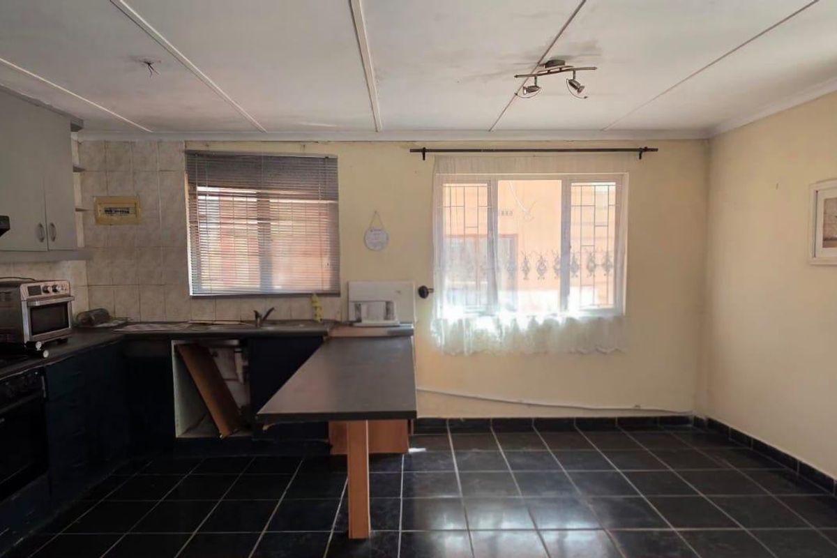 A dated kitchen featuring dark cabinetry, tiled flooring, and built-in appliances, offering significant potential for modernization and renovation.