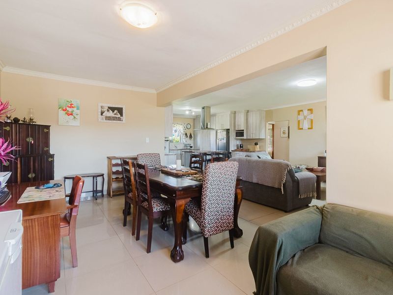 Spacious open-plan living and dining area featuring tiled floors, crown molding, and a seamless transition into a functional kitchen with built-in cabinetry.