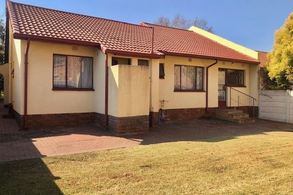 Rear view of the house featuring a paved patio area, brick-base exterior walls, tiled roof, and access to the garden.