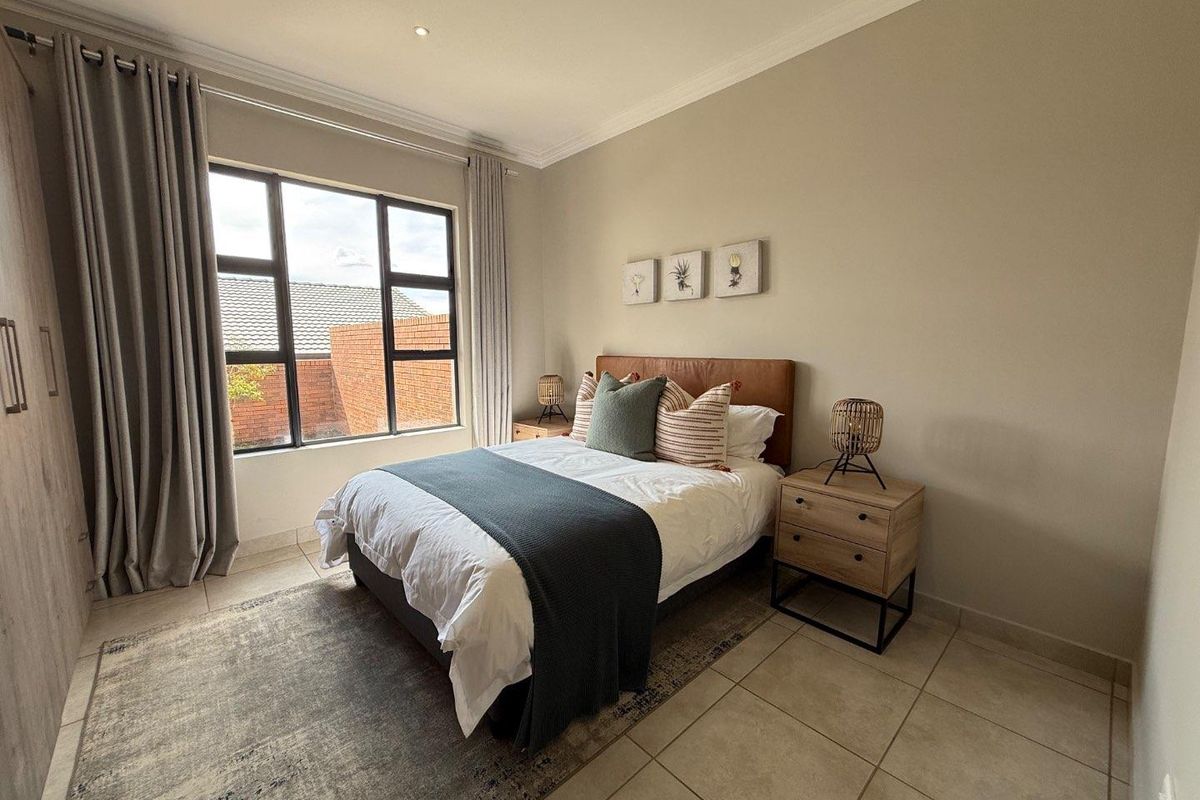 A well-maintained bedroom featuring tiled flooring, built-in cupboards, and large windows that provide natural light.