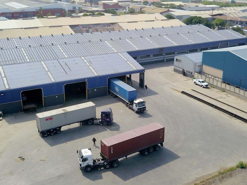 Aerial view of an industrial warehouse facility featuring multiple loading bays, expansive yard space, and metal roofing structure.