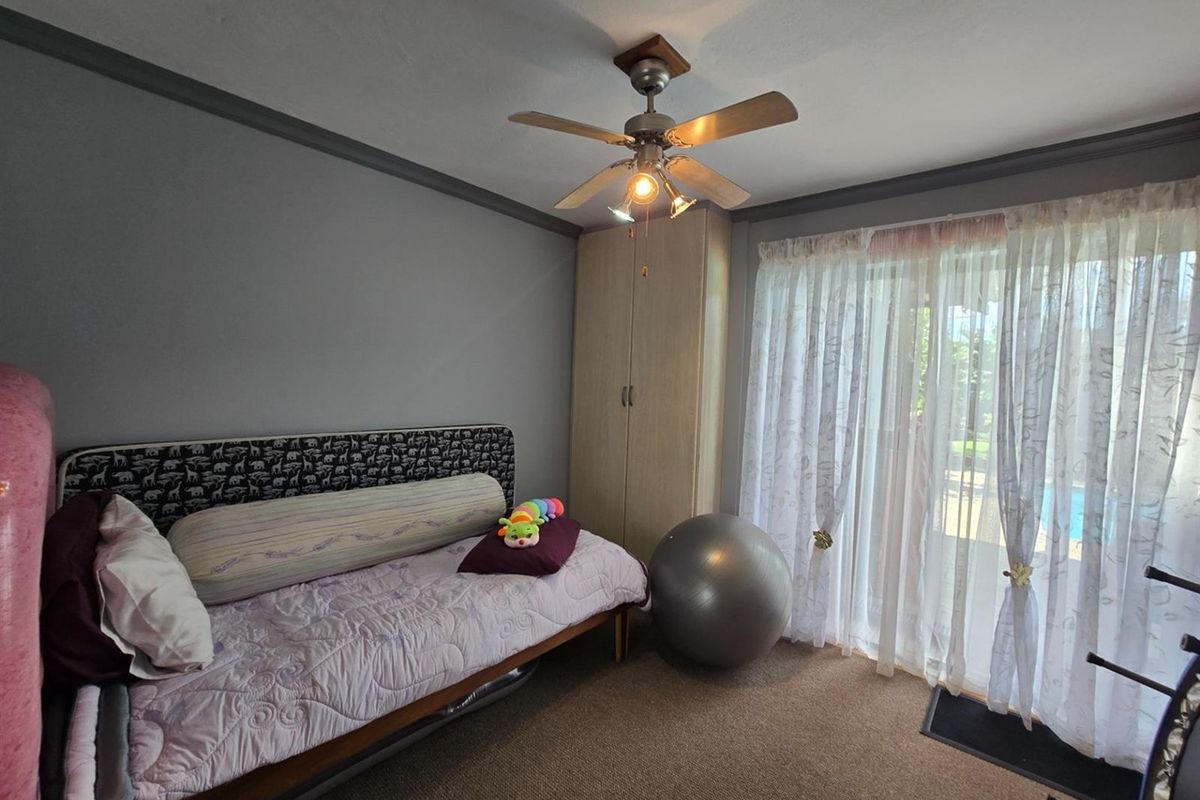 A bedroom featuring carpet flooring, a built-in wardrobe, a ceiling fan, and sliding glass doors providing access to the outdoor area.