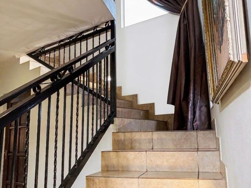 A staircase featuring tiled steps and a decorative wrought iron balustrade leading to the upper level of the home.
