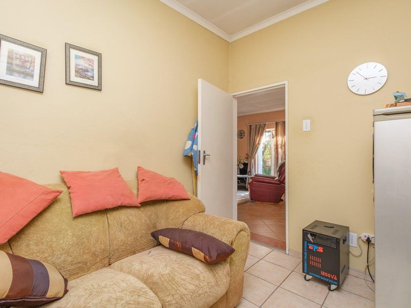 A living area featuring tiled flooring and coved cornicing, with a doorway leading through to an adjacent room.