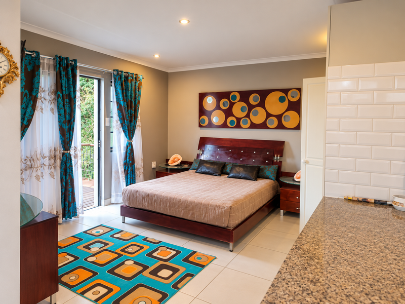 A well-maintained bedroom featuring tiled flooring, recessed lighting, and a sliding glass door providing access to an outdoor area.