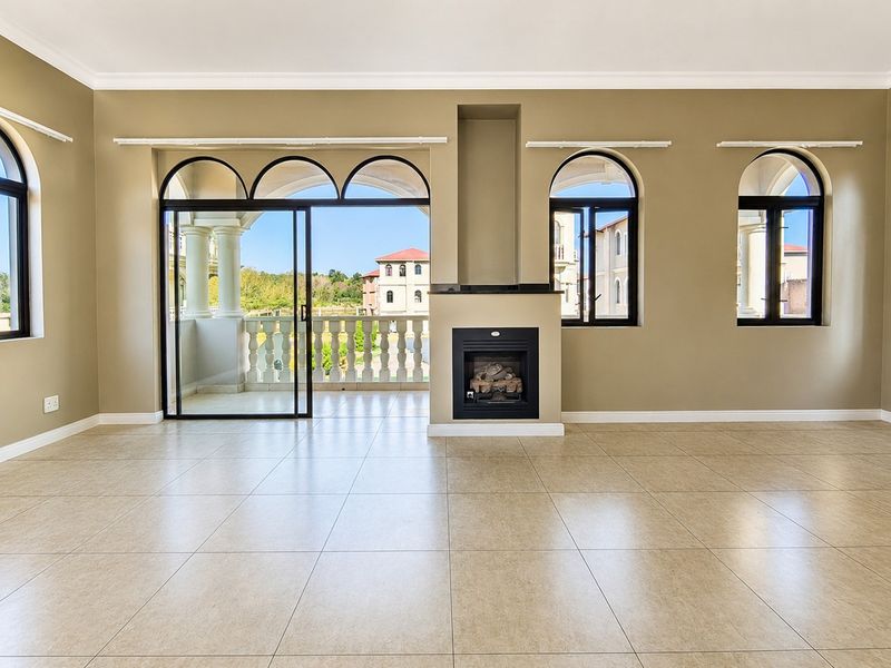 Spacious living room featuring tiled floors, a built-in fireplace, and large arched windows with direct access to a balcony.