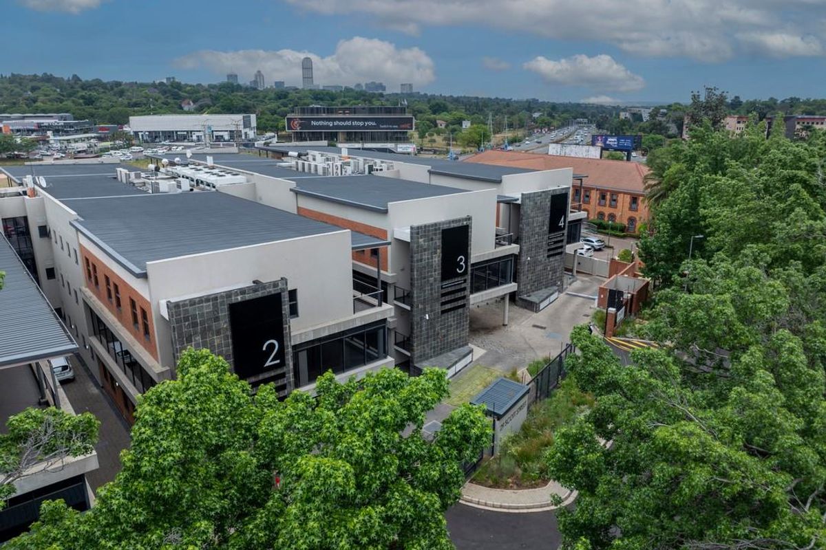 Aerial view of a modern multi-unit office complex featuring stone cladding, flat roofing with HVAC systems, and secure gated access.