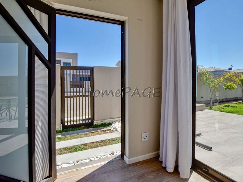 View from an interior space looking out onto a tiled patio, garden area, and secure gated entrance.