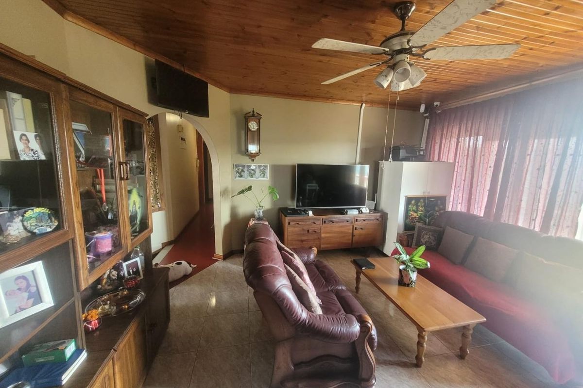 A living room featuring a timber tongue and groove ceiling, ceiling fan, tiled flooring, and an arched doorway leading to the hallway.