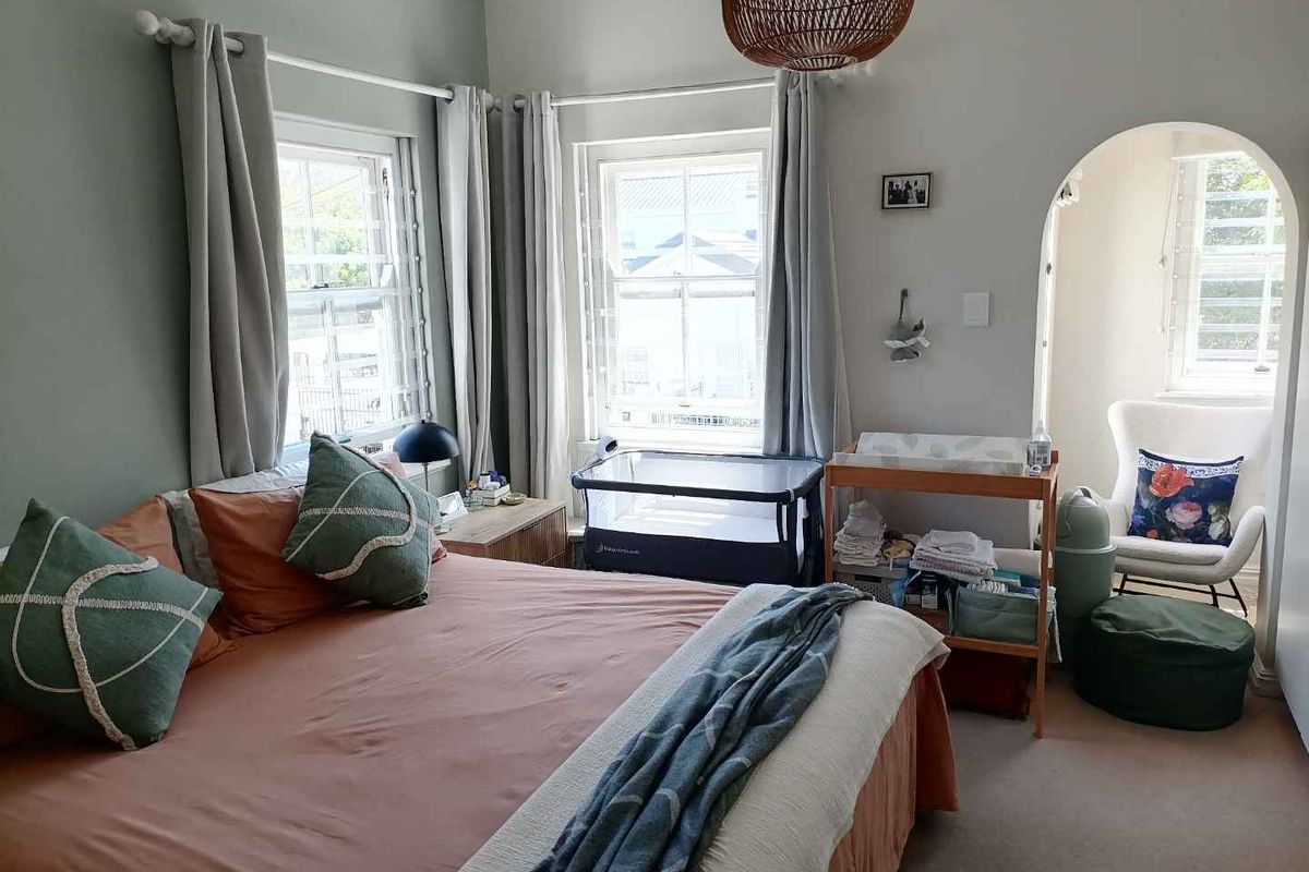 A well-lit bedroom featuring sash windows, neutral wall tones, and an arched alcove area, providing a comfortable and functional living space.