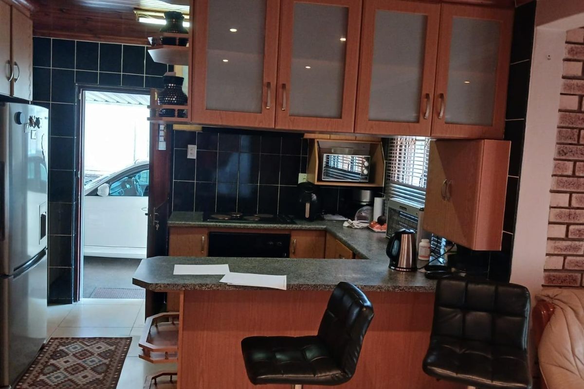 A functional kitchen featuring timber cabinetry, laminate countertops, a tiled backsplash, and a timber ceiling, with an integrated breakfast bar area.