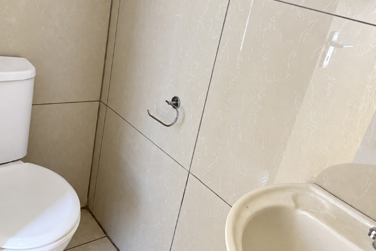 A compact bathroom featuring ceramic wall and floor tiling, a pedestal basin, and a standard toilet.