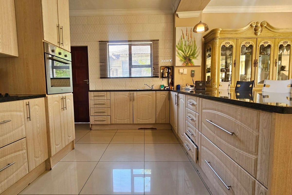 A well-maintained kitchen featuring light wood-finish cabinetry, dark granite countertops, tiled flooring, and a built-in oven.