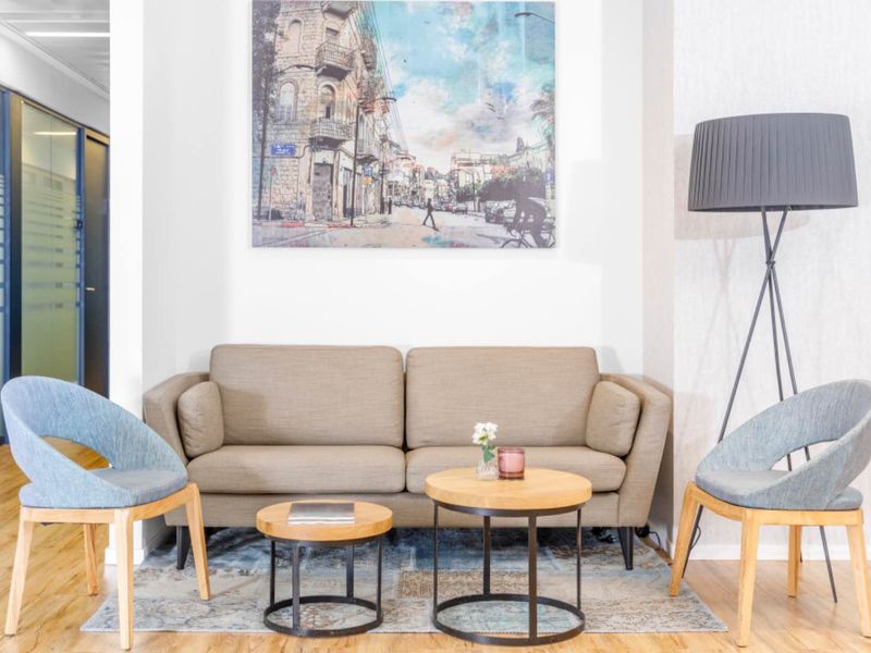 A modern office reception or breakout area featuring laminate flooring and a glass partition wall, creating a professional and welcoming workspace environment.