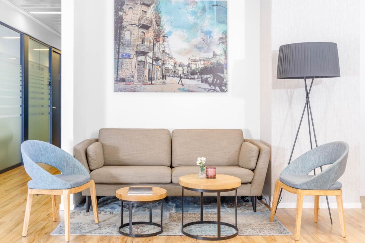 A modern office reception or breakout area featuring laminate flooring and a glass partition wall, creating a professional and welcoming workspace environment.