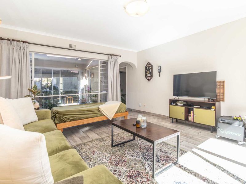 A bright living room featuring tiled flooring, a large sliding glass door providing natural light, and an archway leading to other areas of the home.