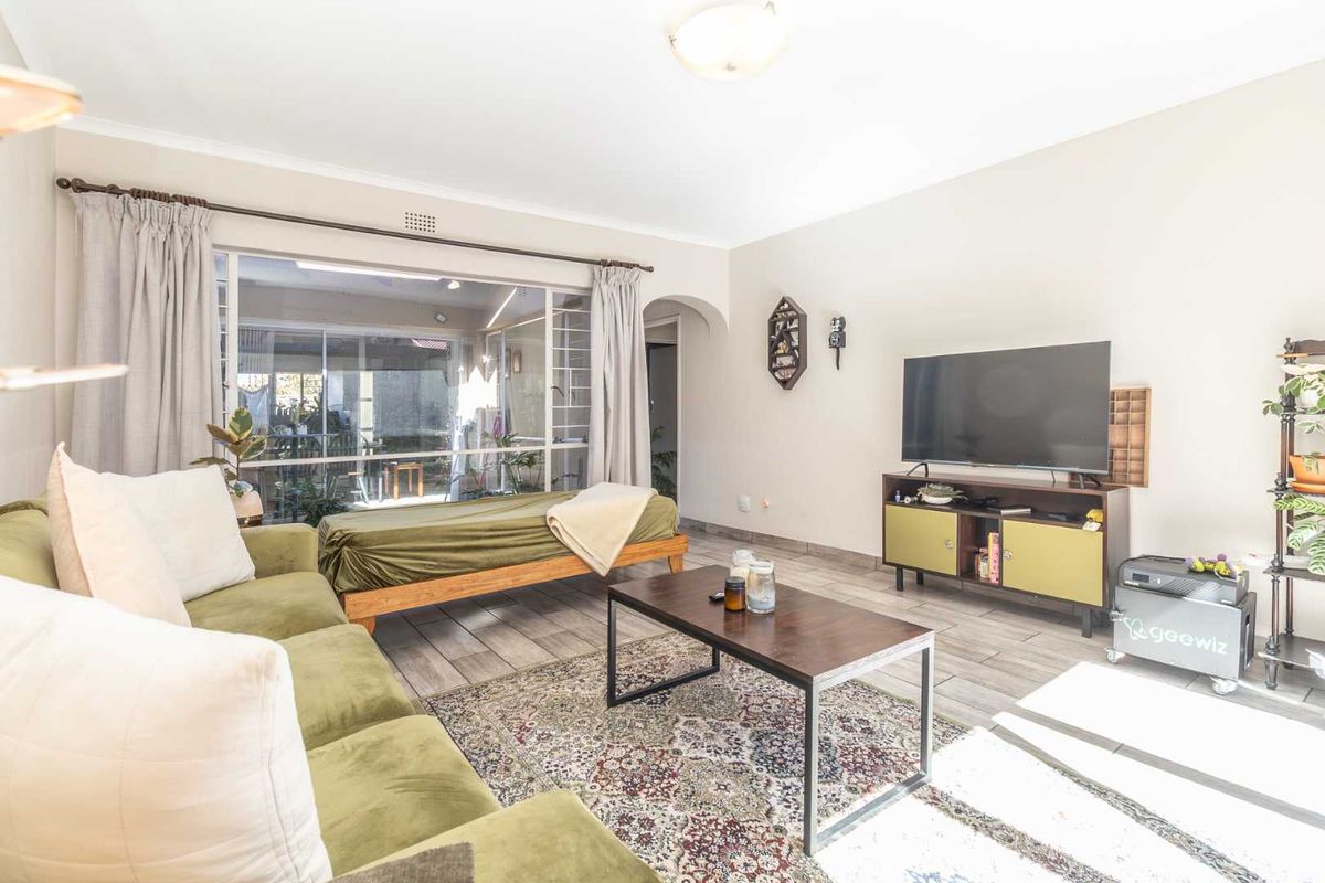 A bright living room featuring tiled flooring, a large sliding glass door providing natural light, and an archway leading to other areas of the home.
