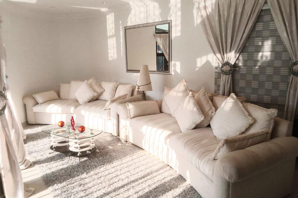 A bright and airy living room featuring recessed ceiling lighting and large windows with elegant drapery, creating a comfortable and inviting atmosphere.