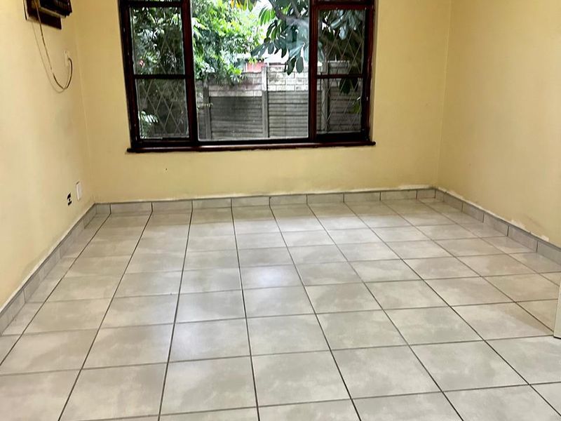 An empty living room featuring tiled flooring, a ceiling fan, and a window air conditioning unit, ready for renovation or staging.