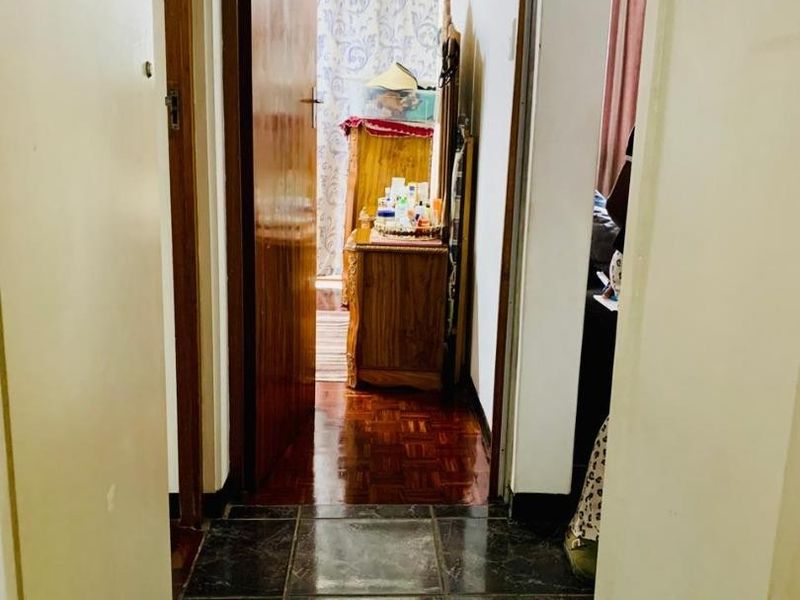 A transitional hallway area featuring a mix of dark tiled and wooden parquet flooring, connecting multiple rooms within the apartment.