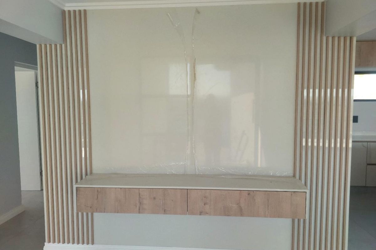 A modern living room feature wall with vertical timber slats and a floating storage unit, presenting a clean, contemporary aesthetic.