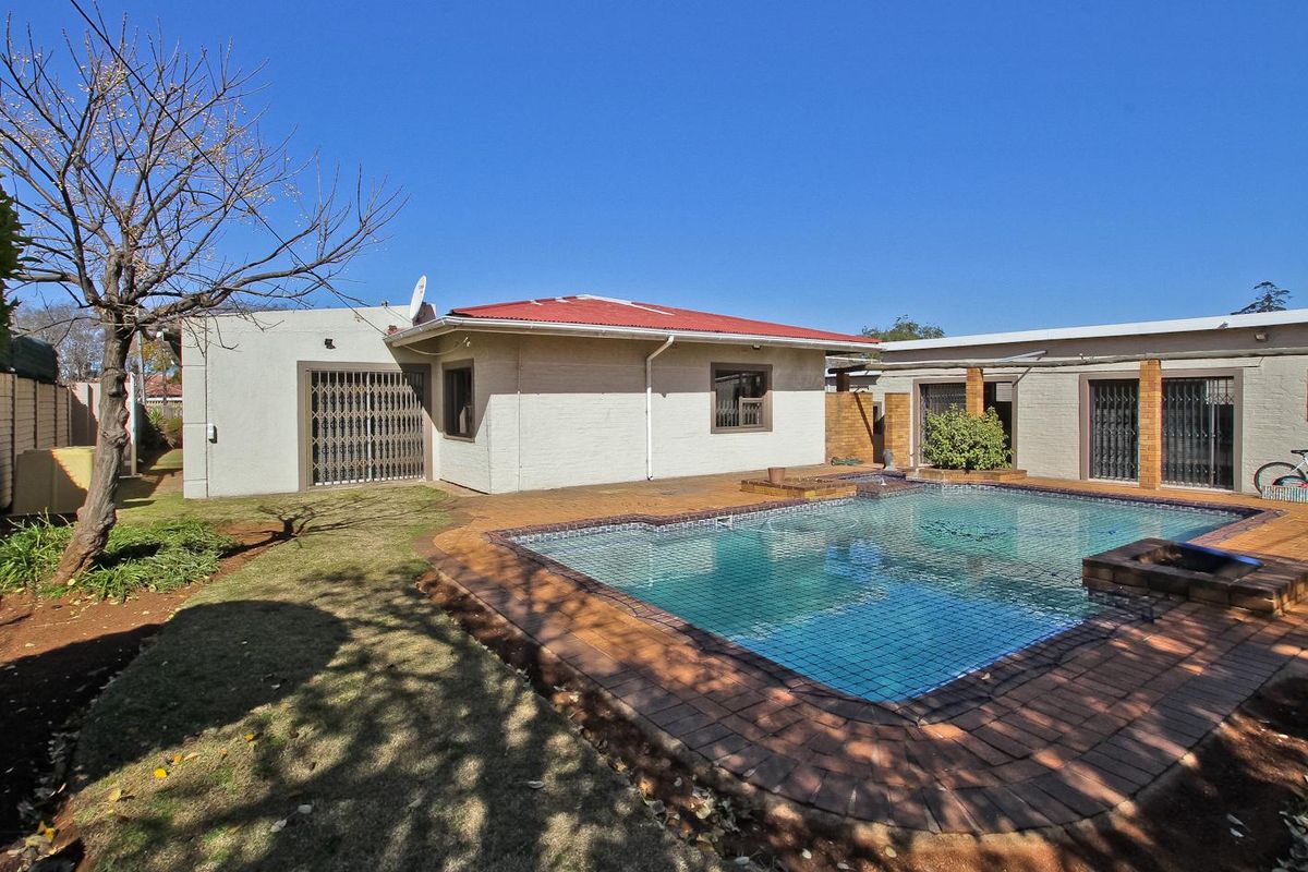 Rear exterior view of the property featuring a swimming pool, brick paved surround, and access to the main dwelling via sliding doors.
