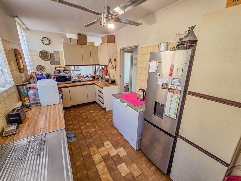 A functional kitchen featuring laminate countertops, tiled backsplash, and built-in cabinetry, offering a practical layout with potential for modern updates.