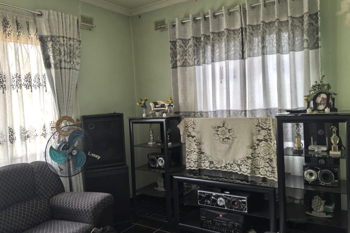 A living room area featuring tiled flooring and wall-mounted air vents, currently showing signs of wear and dated interior finishes.