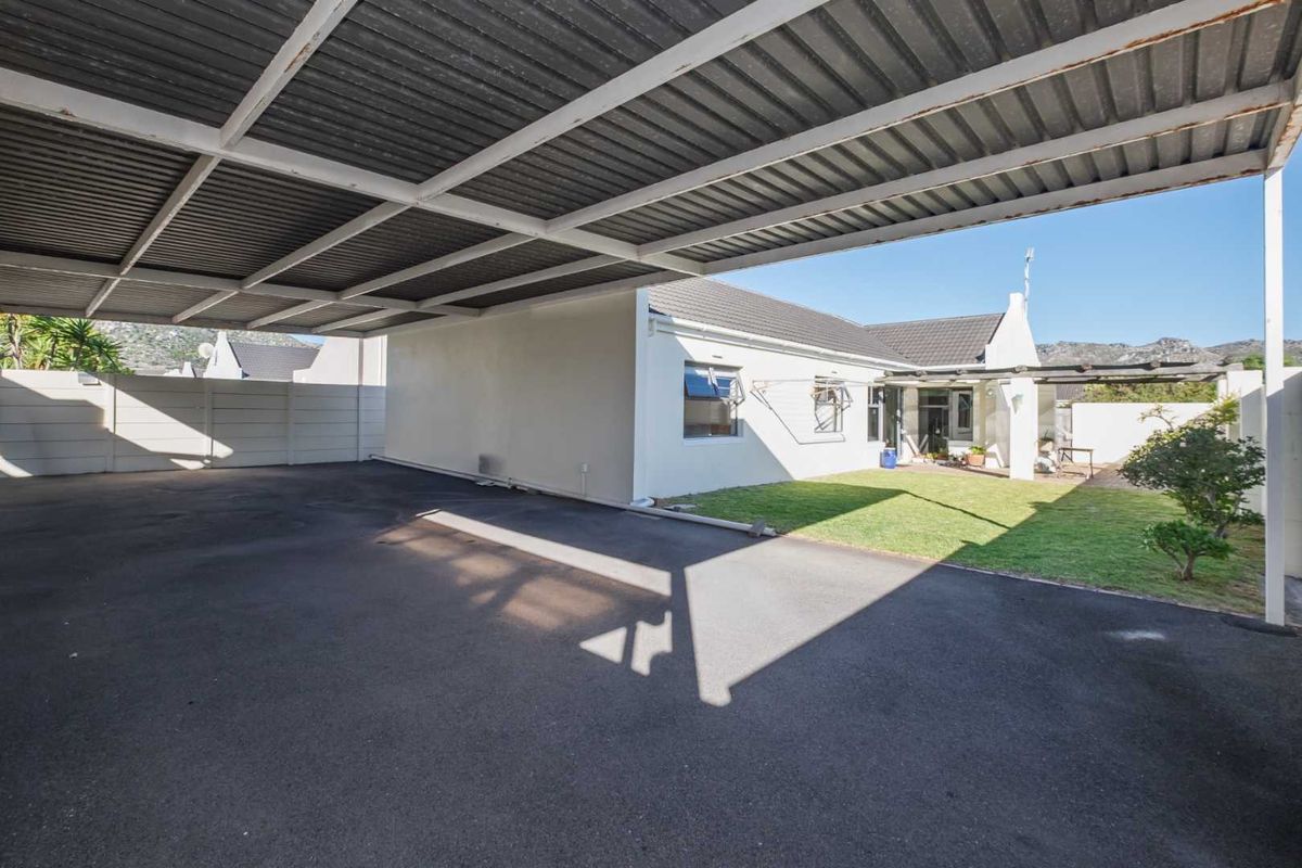 A spacious paved carport area adjacent to a private garden and the rear elevation of the house.