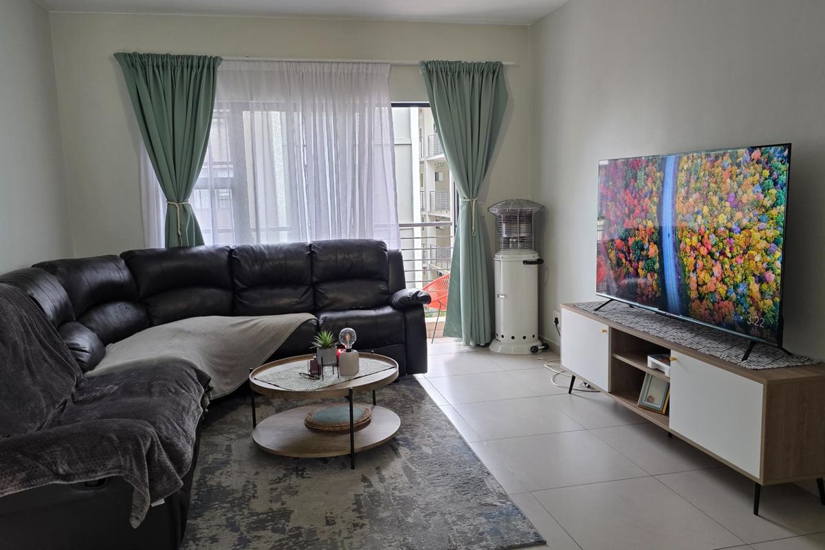 A bright living room featuring tiled flooring, large sliding glass doors leading to a balcony, and neutral wall finishes.