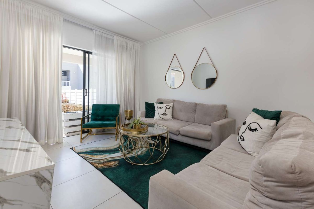 A bright living room featuring large sliding glass doors that open to an outdoor patio area, finished with neutral floor tiles.