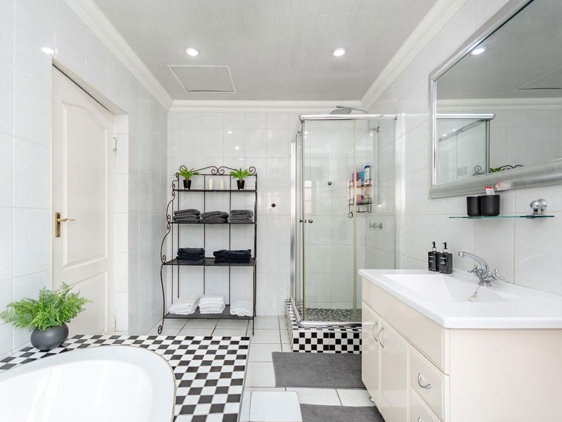 A well-maintained bathroom featuring a shower enclosure, vanity cabinet with basin, and classic black and white checkered floor tiling.