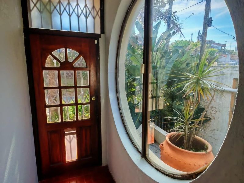 Entrance foyer featuring a distinctive circular window, timber door with security gate, and terracotta tiled flooring.