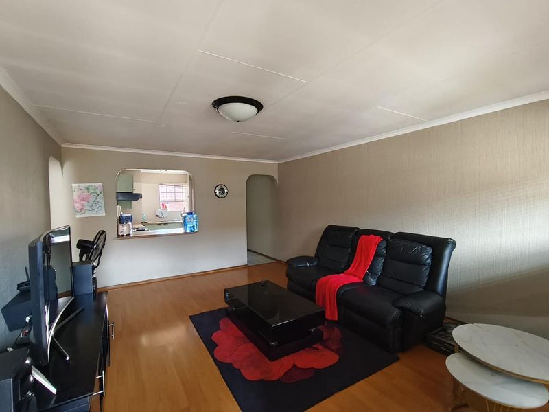 Open plan living area featuring laminate flooring, a kitchen pass-through window, and an arched entryway, providing a functional and connected layout.