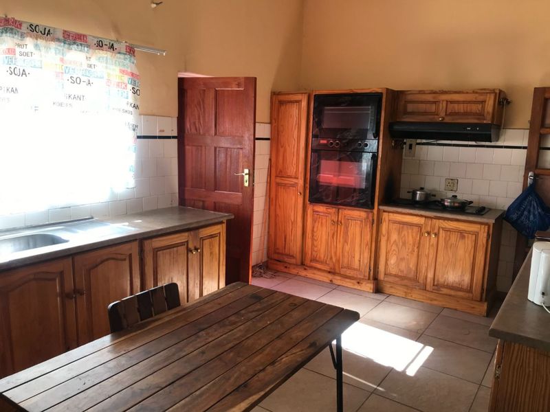 A functional kitchen featuring built-in wooden cabinetry, integrated oven, extractor fan, and tiled splashbacks, offering a traditional aesthetic with ample storage space.