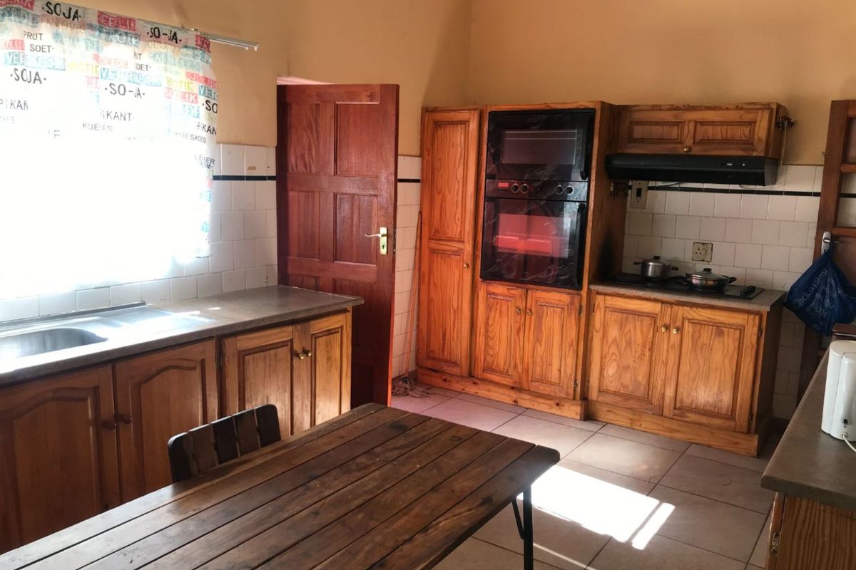A functional kitchen featuring built-in wooden cabinetry, integrated oven, extractor fan, and tiled splashbacks, offering a traditional aesthetic with ample storage space.