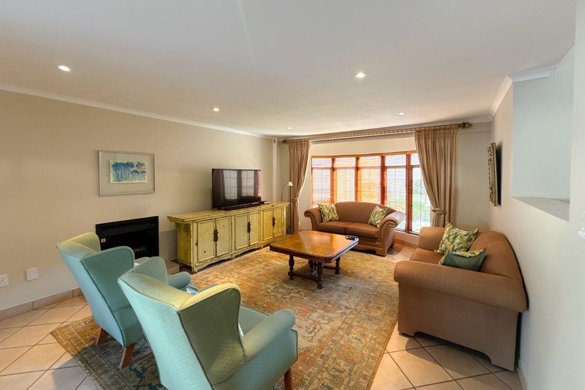 A spacious living room featuring tiled flooring, a built-in fireplace, and a large bay window that allows for ample natural light.
