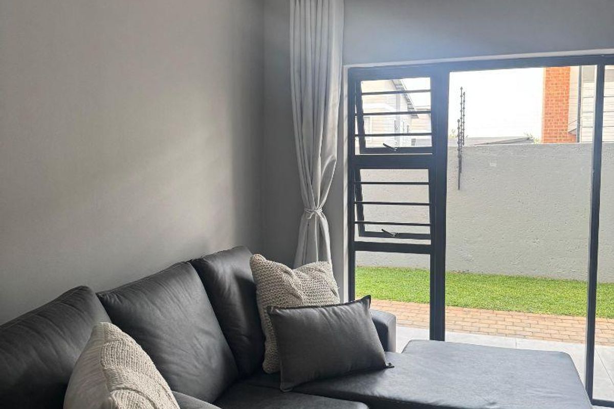 A modern living room featuring laminate flooring and a large sliding glass door providing access to an outdoor patio area.