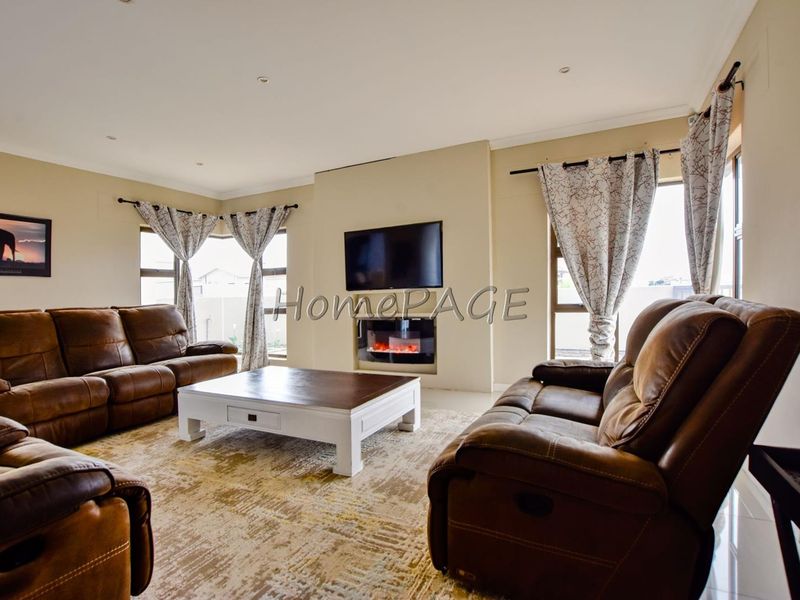 Spacious living room featuring a built-in fireplace, tiled flooring, and large windows that provide ample natural light.