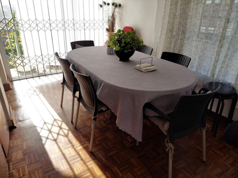 A dining room featuring classic parquet flooring and a large sliding door with a security gate, providing access to the outdoor area.