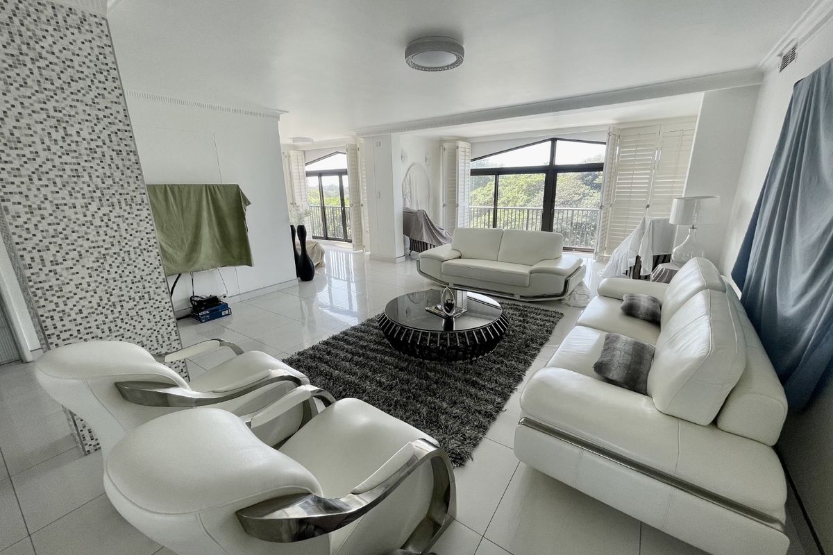 Spacious living room featuring polished tiled floors, a decorative mosaic feature wall, and large glass doors leading to an outdoor balcony area.